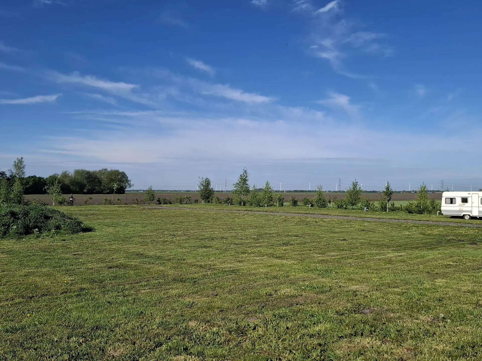 Het weidse kampeerveld van Camping de Veenplagge onder een blauwe lucht